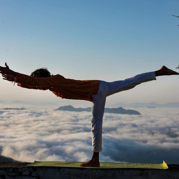 Silhouette of a person in a yoga warrior pose at sunrise.