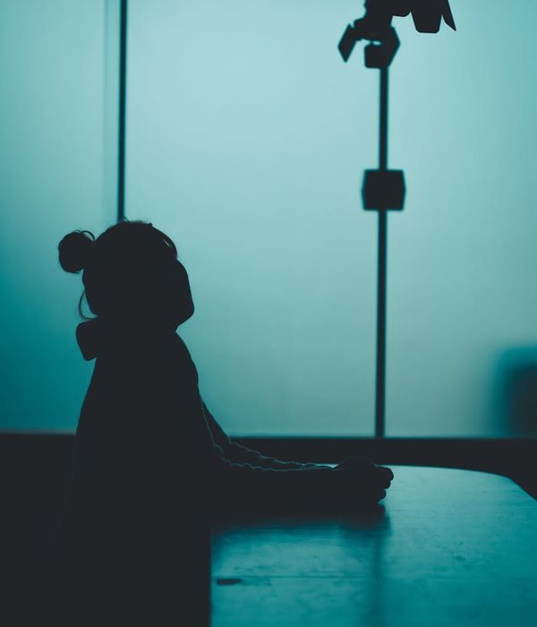 Woman in a peaceful yoga pose against a dark background with blue light.